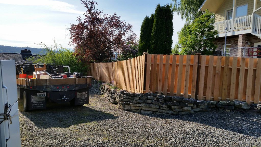 A trailer with tools parked near a residential home with a wooden fence